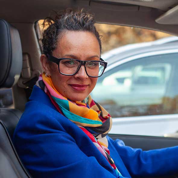 Businesswoman driving car with glasses and smiling